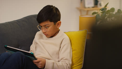 Close-Up-Of-Young-Boy-Sitting-On-Sofa-At-Home-Playing-Games-Or-Streaming-Onto-Digital-Tablet-10